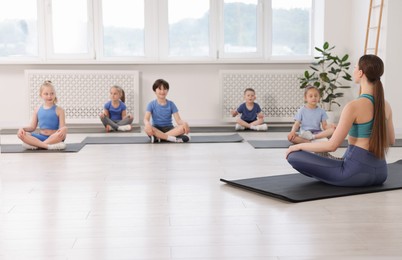 Photo of Group of children practicing yoga with coach on mats in class