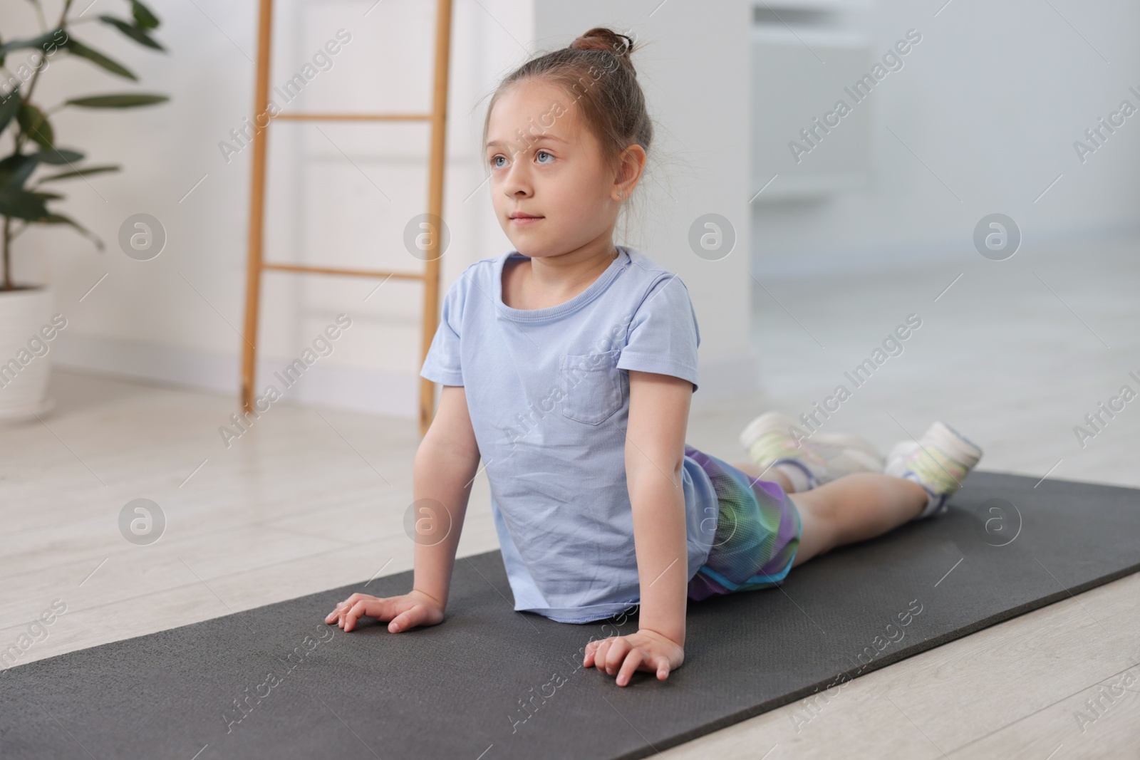 Cute girl practicing yoga on mat indoors Photo of Cute girl practicing yoga on mat indoors