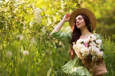Photo of Beautiful woman with bouquet of peonies in park. Space for text