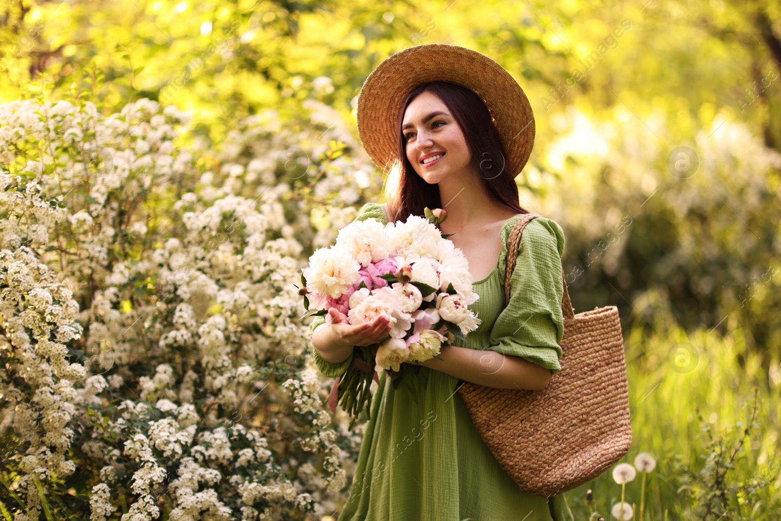 Beautiful woman with bouquet of peonies in park Photo of Beautiful woman with bouquet of peonies in park