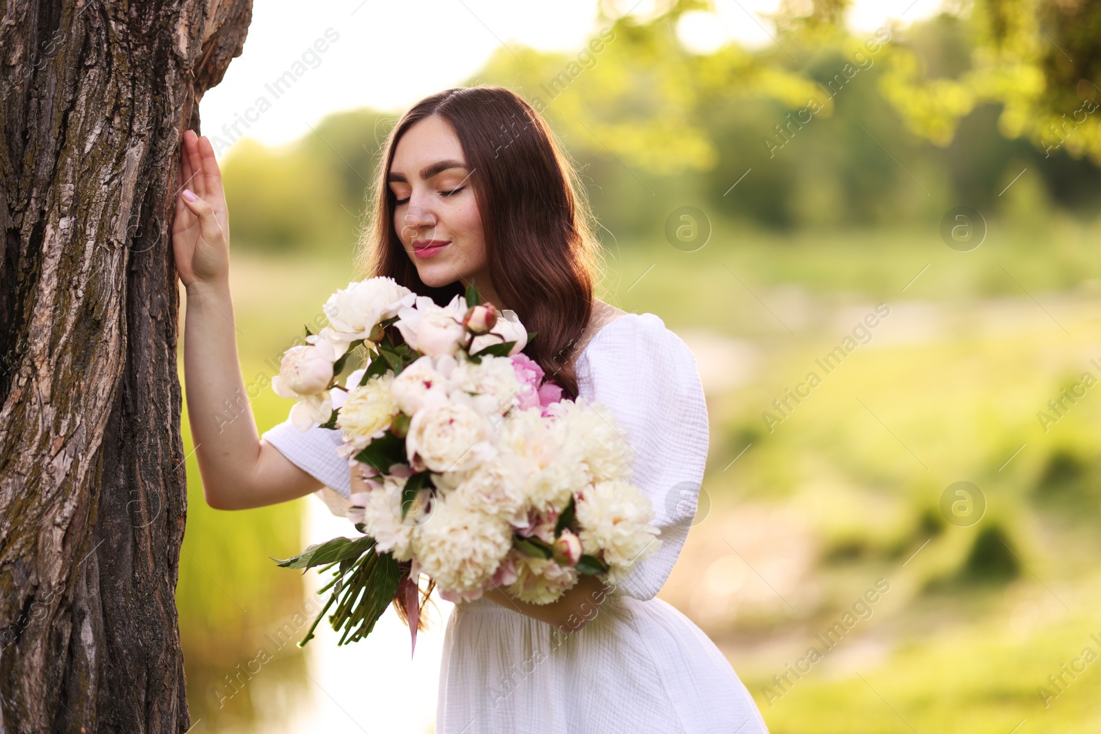 Beautiful woman with bouquet of peonies in park. Space for text Photo of Beautiful woman with bouquet of peonies in park. Space for text