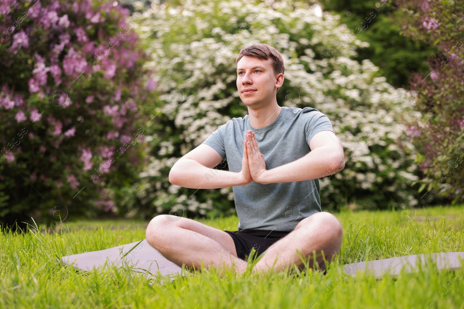 Young man practicing yoga on mat in park Photo of Young man practicing yoga on mat in park