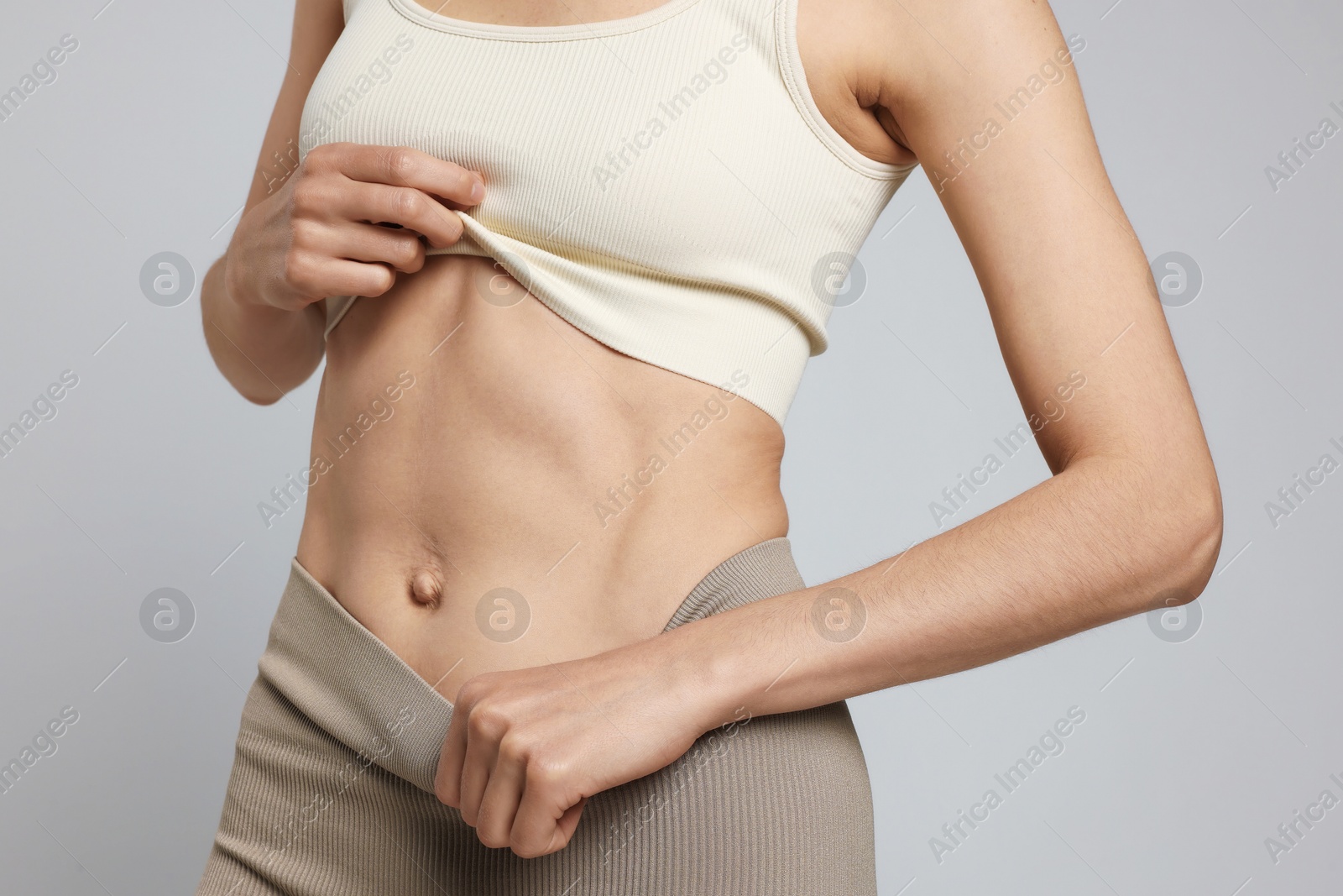 Beautiful woman with flat belly on gray background, closeup Photo of Beautiful woman with flat belly on gray background, closeup