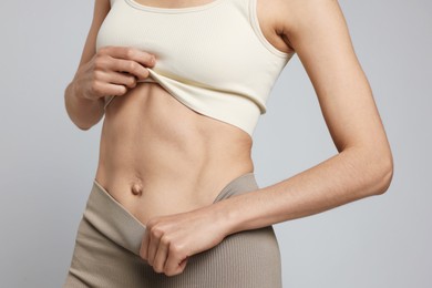 Photo of Beautiful woman with flat belly on gray background, closeup