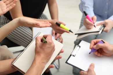 Photo of Group of people writing in notebooks during life coaching class indoors, closeup