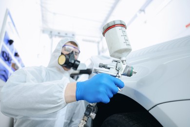 Photo of Worker painting car in body shop, selective focus
