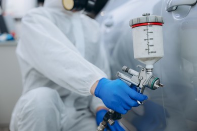 Photo of Worker painting car in body shop, closeup