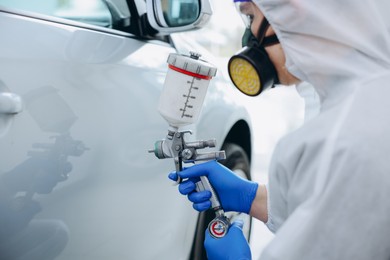 Photo of Worker painting car in body shop, closeup