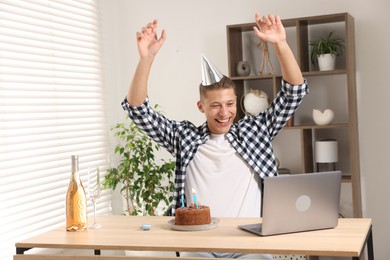 Photo of Happy man celebrating his birthday while having video call at desk indoors