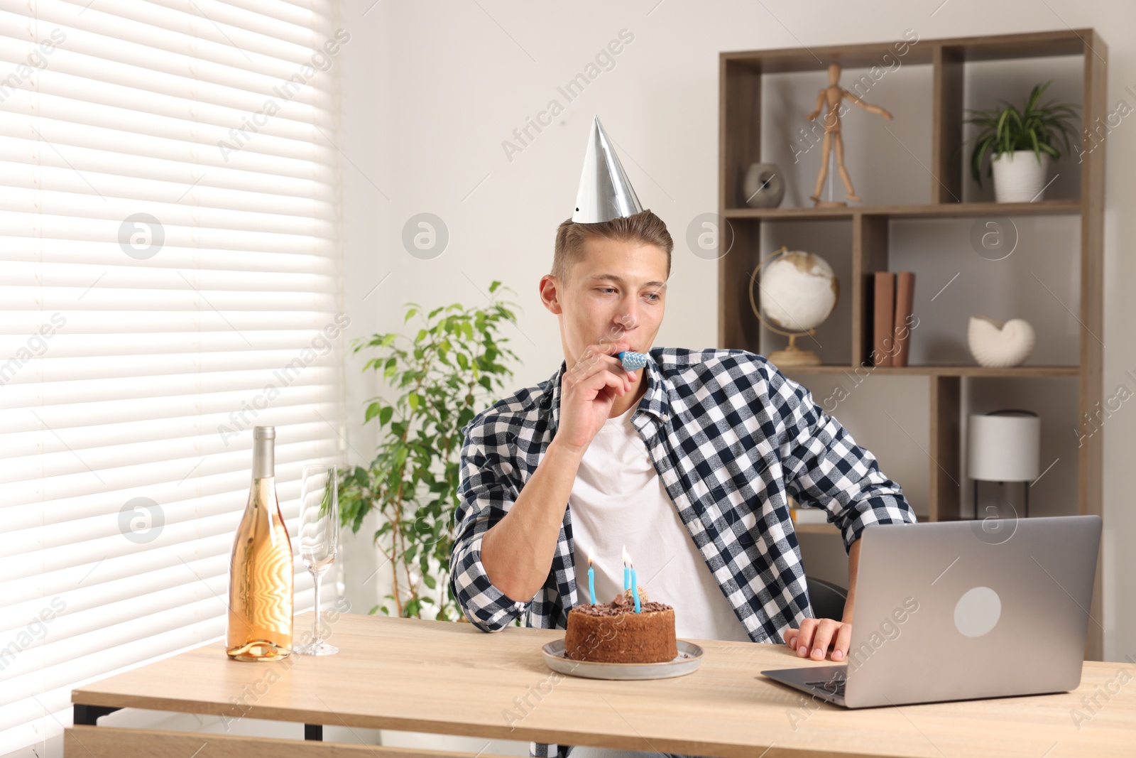 Photo of Happy man celebrating his birthday while having video call at desk indoors
