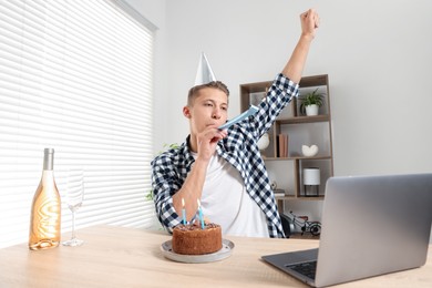 Photo of Happy man celebrating his birthday while having video call at desk indoors