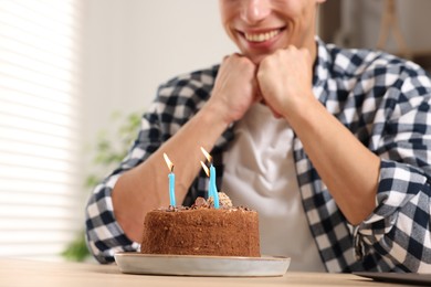 Photo of Birthday celebration. Man with cake having video call via laptop at desk indoors, closeup