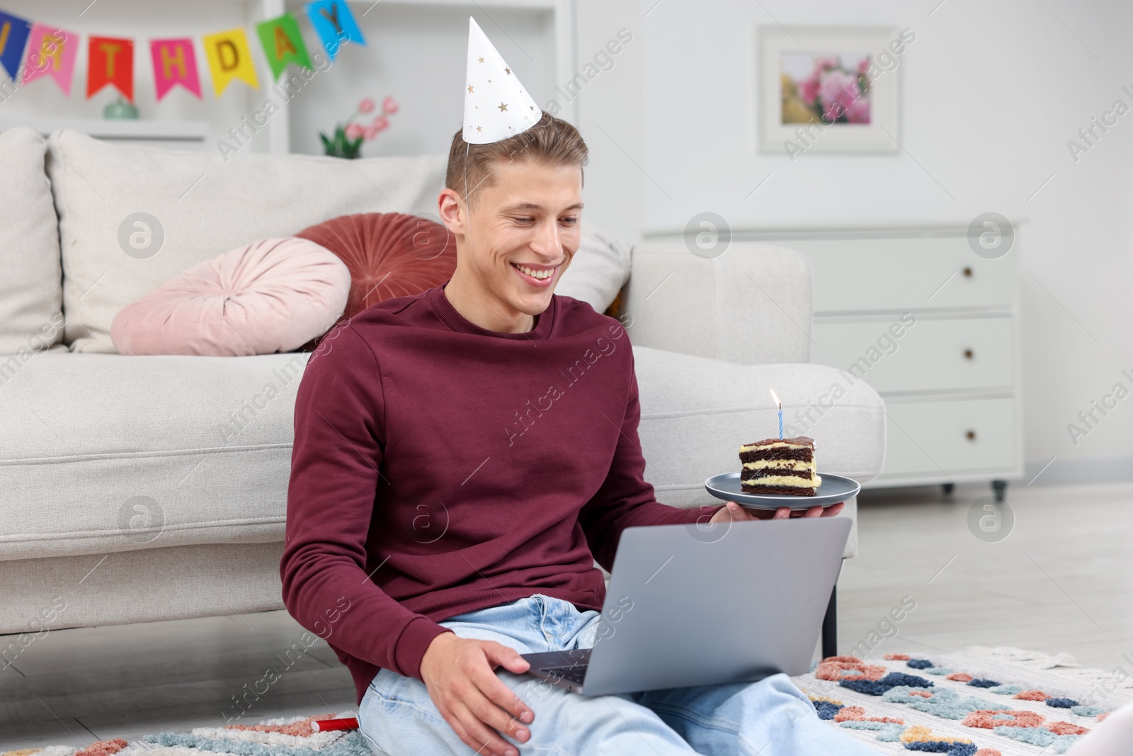 Photo of Man with piece of cake celebrating his birthday and having video call via laptop at home
