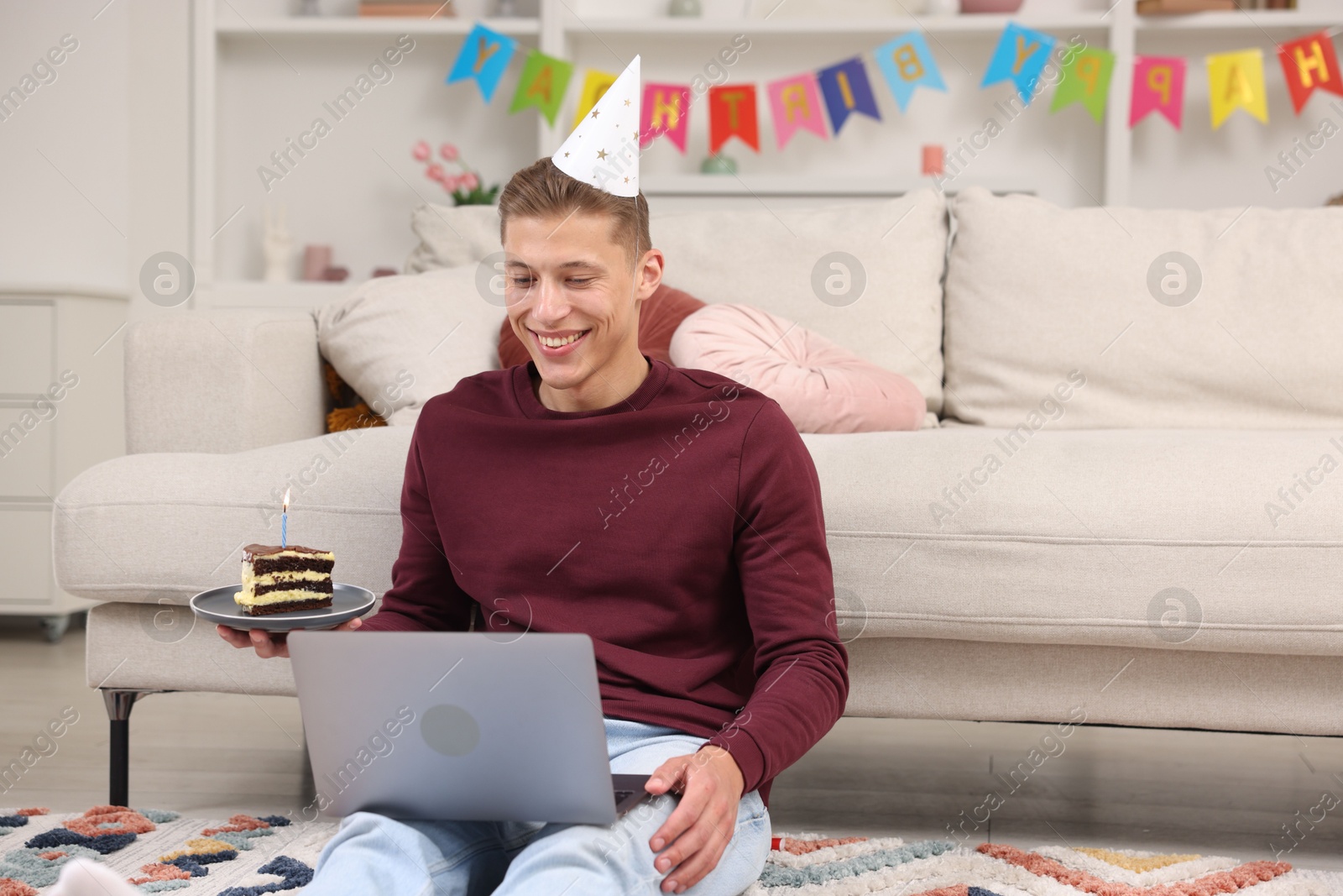 Photo of Man with piece of cake celebrating his birthday and having video call via laptop at home