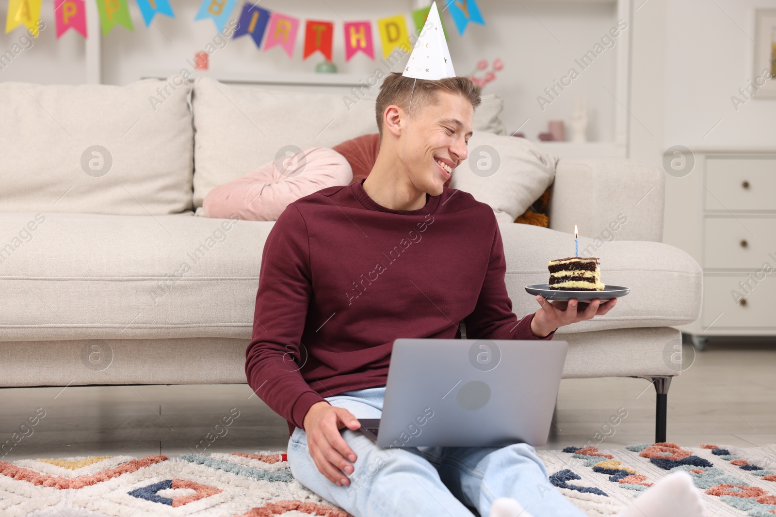 Photo of Man with piece of cake celebrating his birthday and having video call via laptop at home