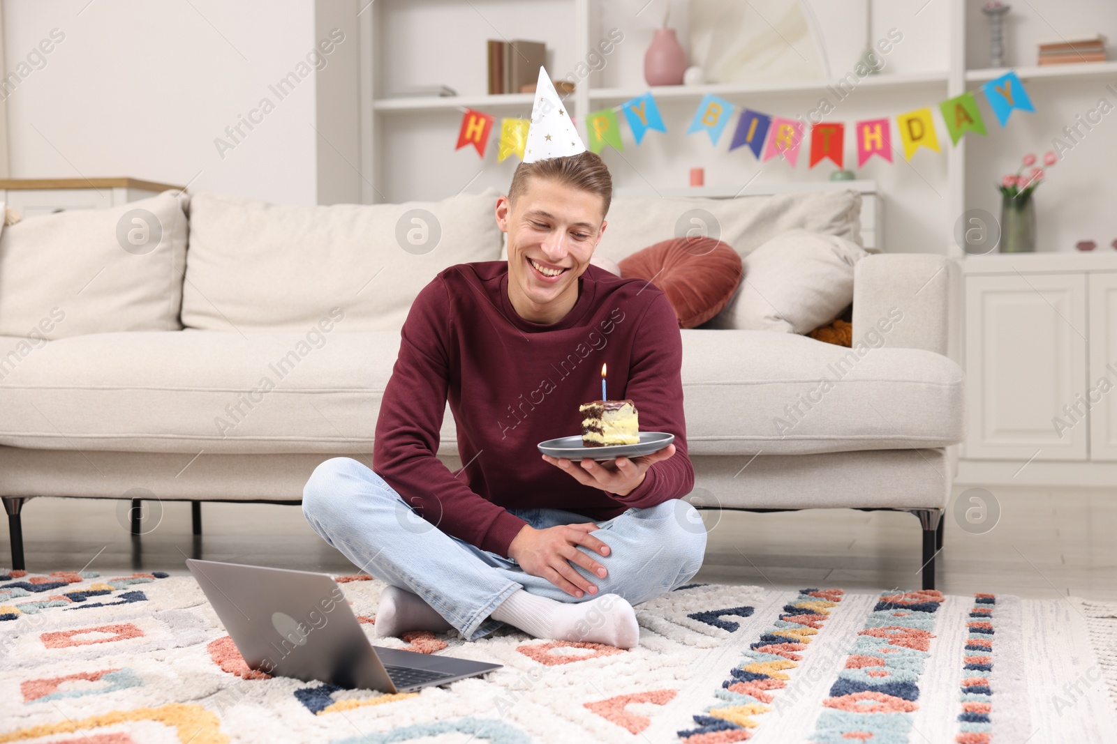 Photo of Man with piece of cake celebrating his birthday and having video call via laptop at home