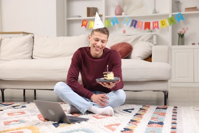 Photo of Man with piece of cake celebrating his birthday and having video call via laptop at home