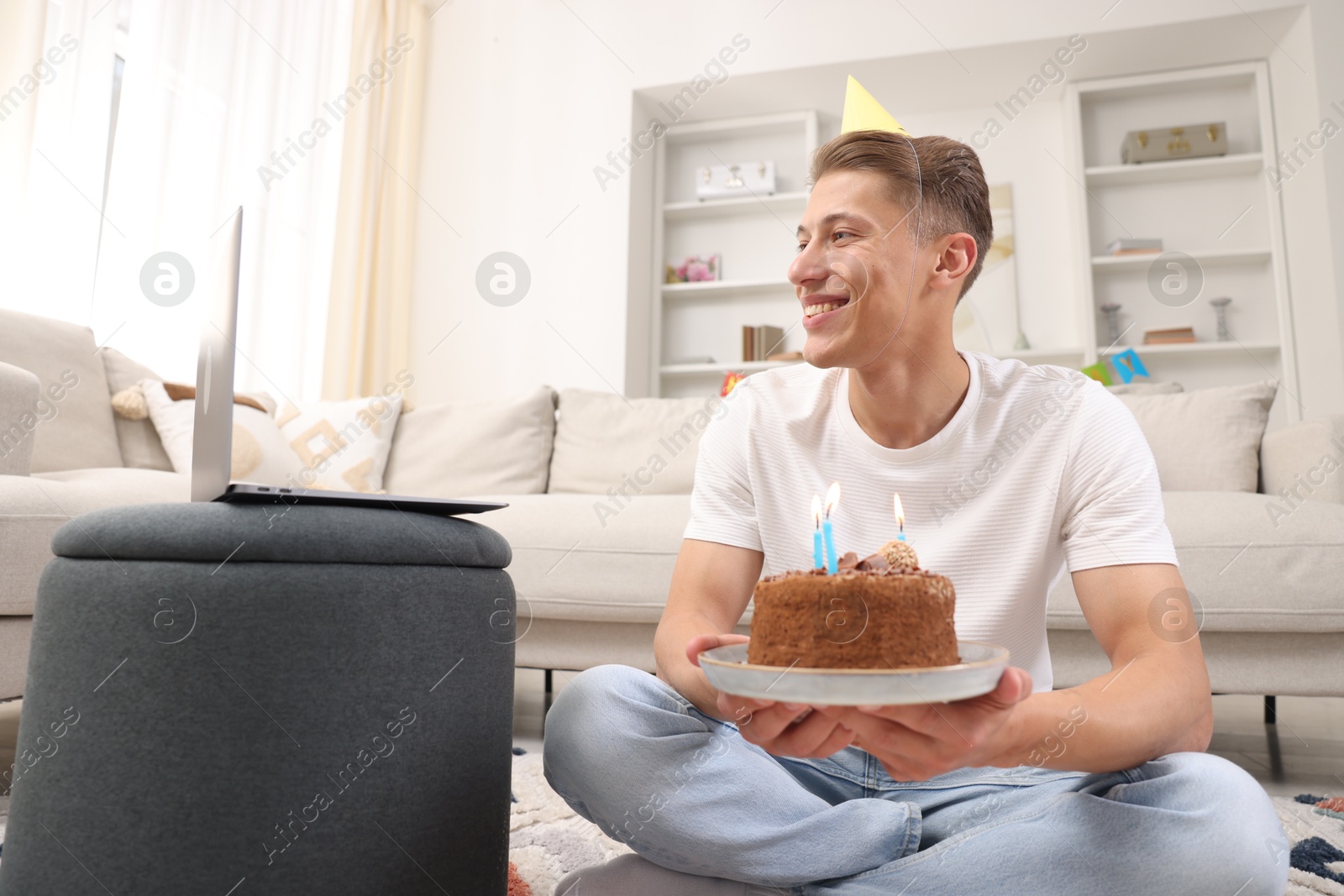 Photo of Man with cake celebrating his birthday and having video call via laptop at home