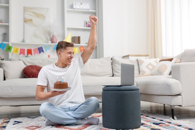 Photo of Man with cake celebrating his birthday and having video call via laptop at home