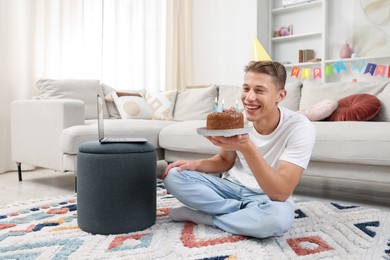Photo of Man with cake celebrating his birthday and having video call via laptop at home