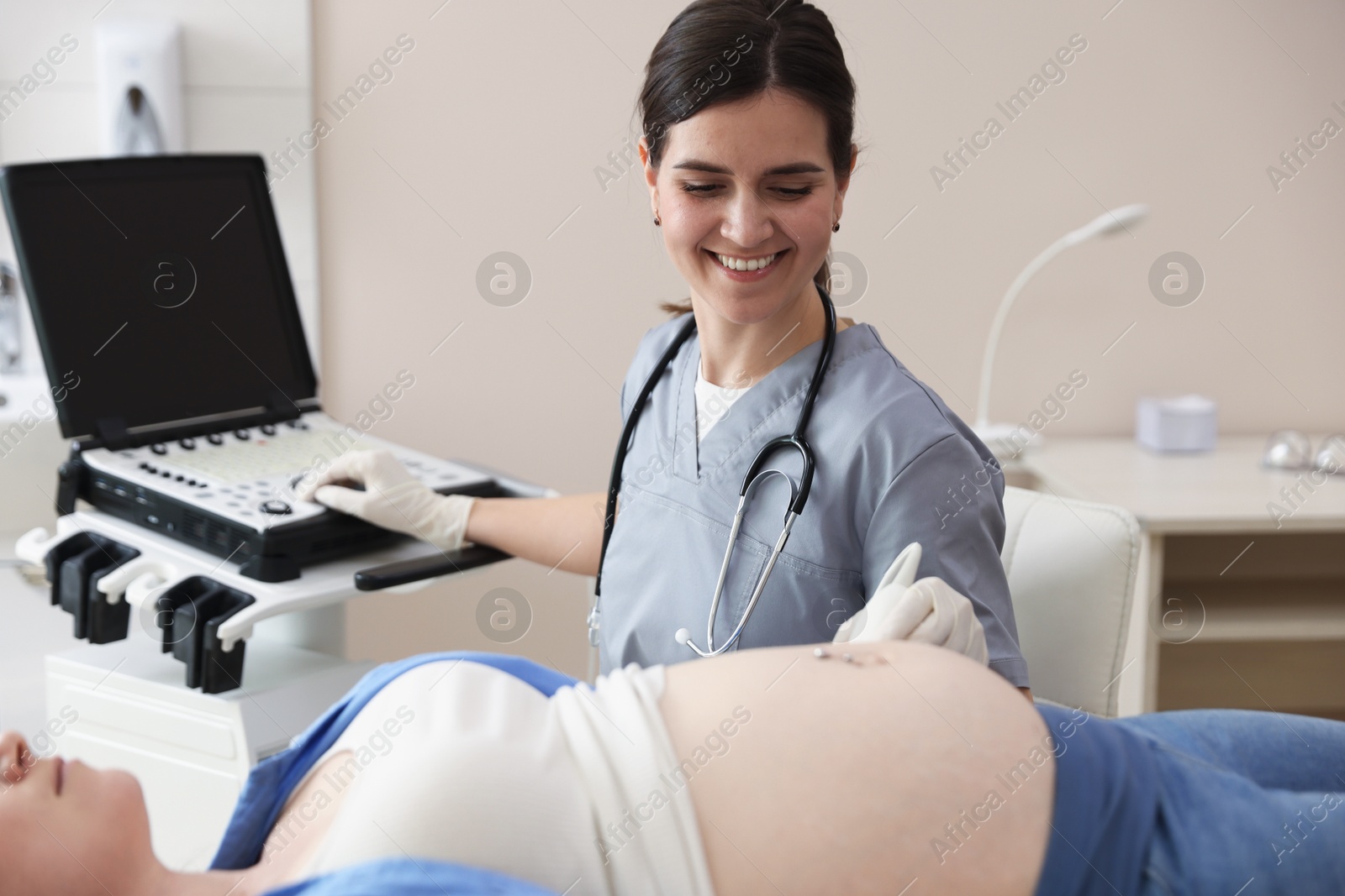 Photo of Sonographer conducting woman's prenatal ultrasound examination in clinic