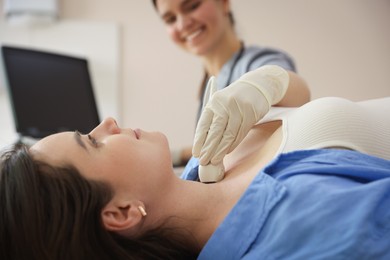 Photo of Sonographer conducting ultrasound examination of woman's thyroid gland in clinic, closeup