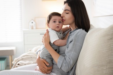 Photo of Mother kissing her cute baby on sofa at home. Space for text