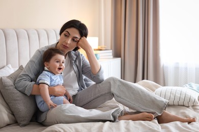 Photo of Woman suffering from postpartum depression with her little baby on bed at home. Space for text