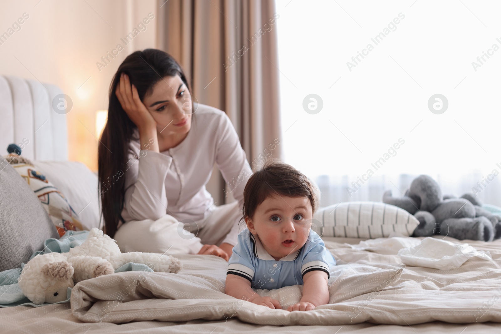 Photo of Woman suffering from postpartum depression with her little baby on bed at home. Space for text