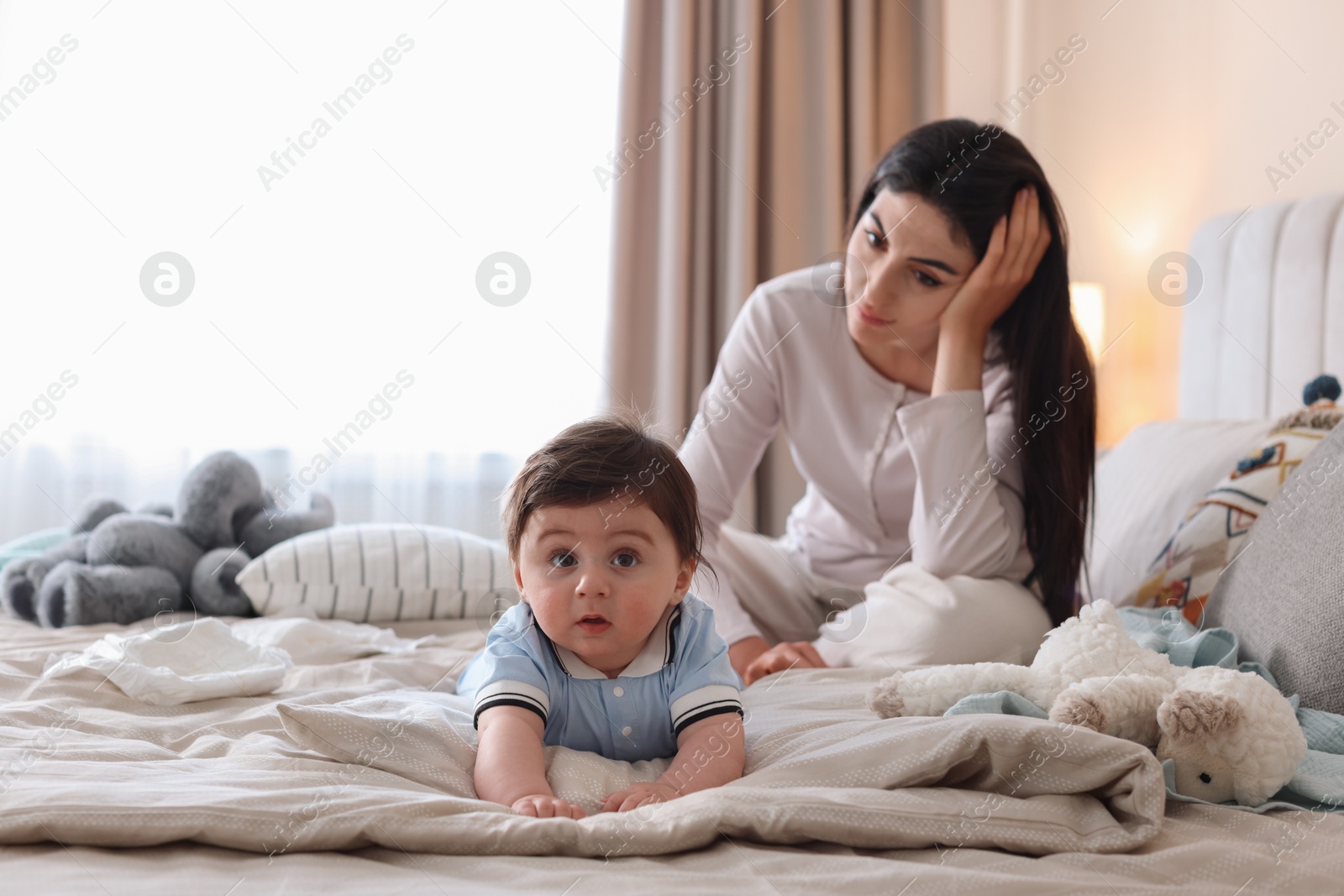 Photo of Woman suffering from postpartum depression with her little baby on bed at home. Space for text