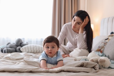 Photo of Woman suffering from postpartum depression with her little baby on bed at home. Space for text
