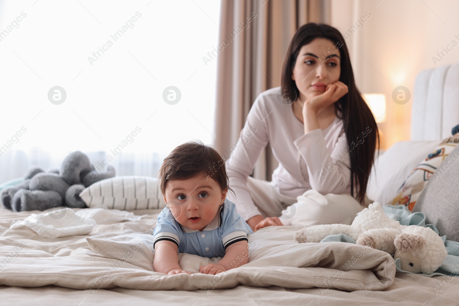 Photo of Woman suffering from postpartum depression with her little baby on bed at home. Space for text