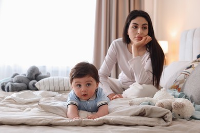 Photo of Woman suffering from postpartum depression with her little baby on bed at home. Space for text