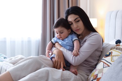 Photo of Woman suffering from postpartum depression with her little baby on bed at home. Space for text