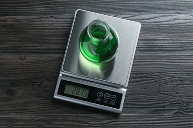 Photo of Laboratory scale with flask of sample on wooden table, top view