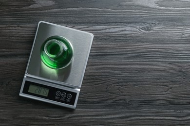Photo of Laboratory scale with flask of sample on wooden table, top view. Space for text