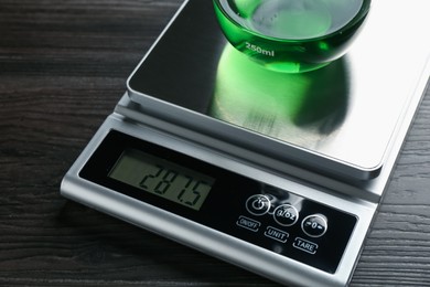 Photo of Laboratory scale with flask of sample on wooden table, closeup