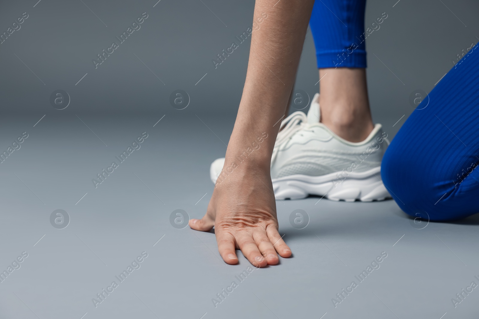 Runner in starting position on gray background, closeup. Space for text Photo of Runner in starting position on gray background, closeup. Space for text