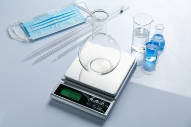 Photo of Scale with flask and other laboratory equipment on white background