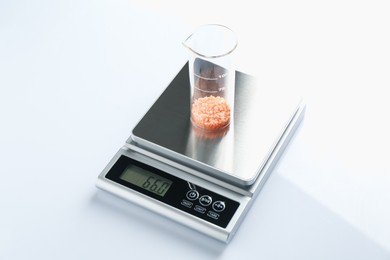 Photo of Laboratory scale with beaker of sample on white background