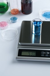 Photo of Scale with beaker of sample and other laboratory equipment on white background