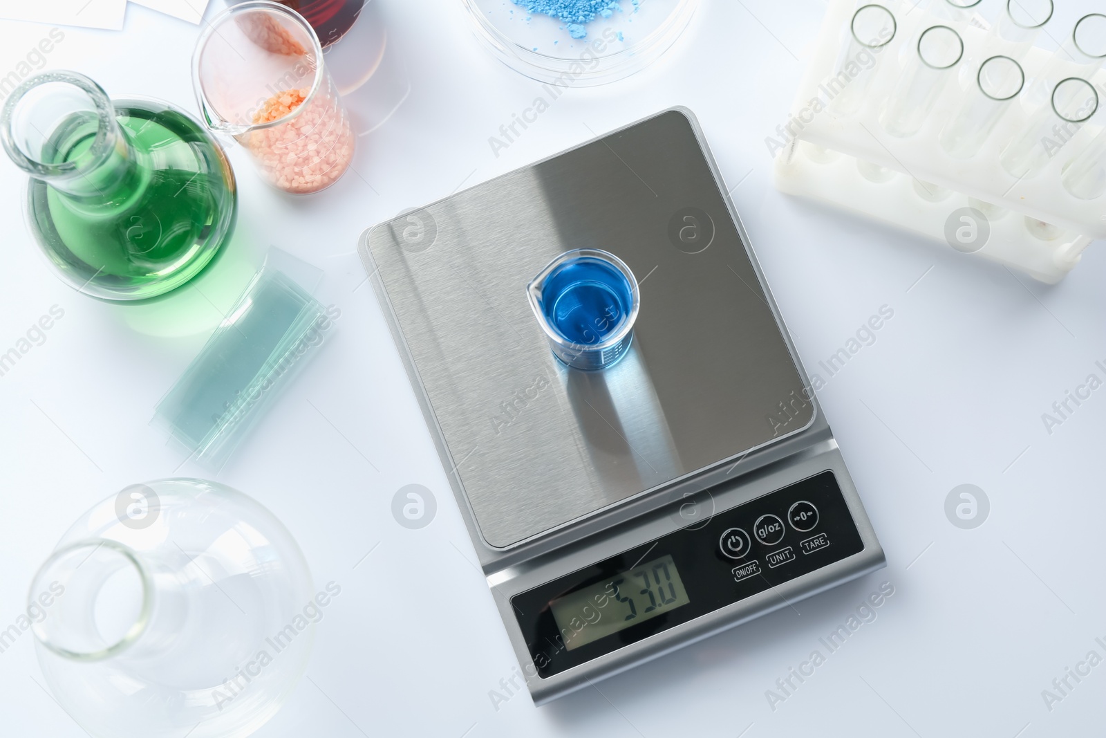Scale with beaker of sample and other laboratory equipment on white background, flat lay Photo of Scale with beaker of sample and other laboratory equipment on white background, flat lay