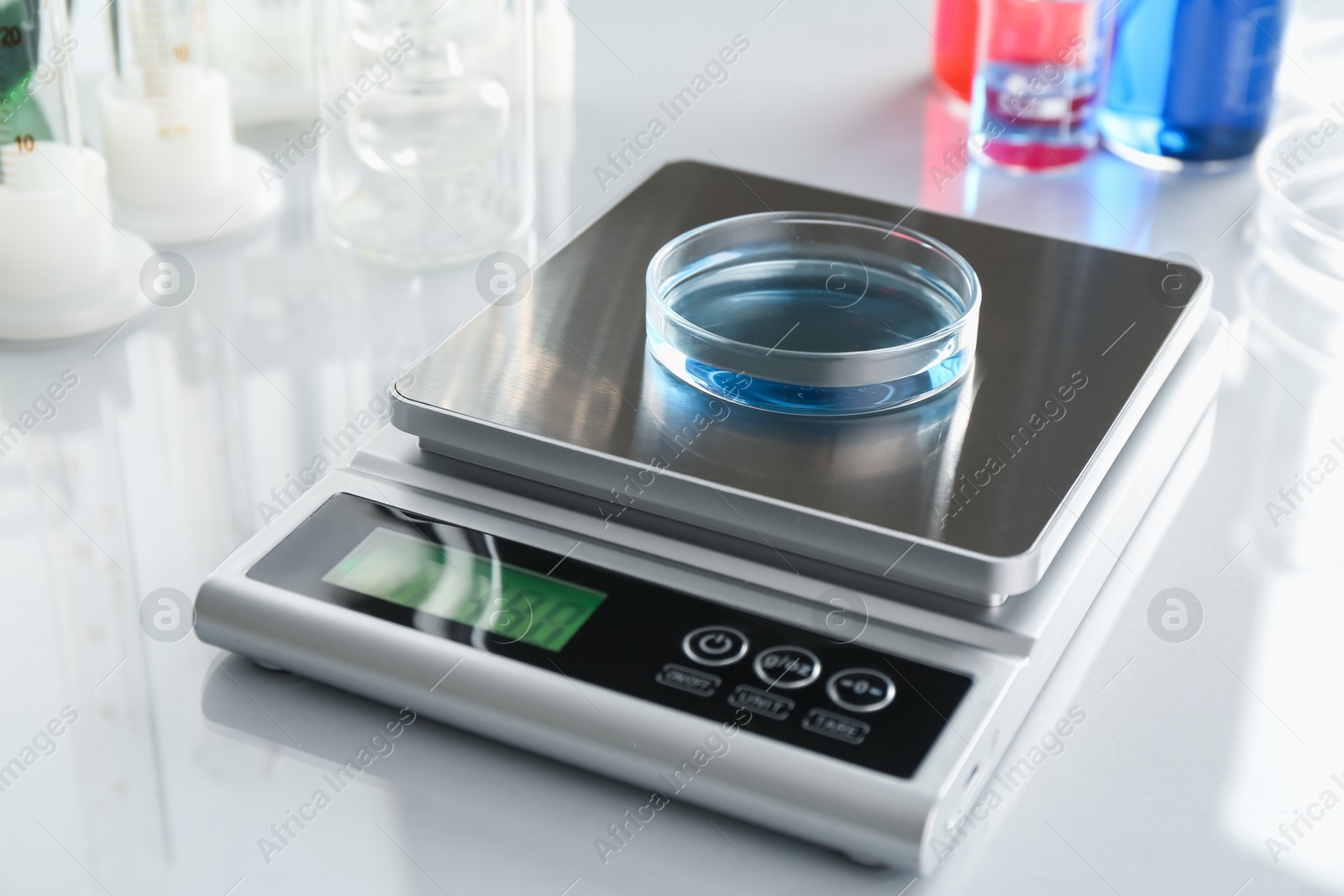Scale with Petri dish of sample and other laboratory glassware on white mirror table, closeup Photo of Scale with Petri dish of sample and other laboratory glassware on white mirror table, closeup