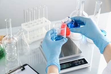 Photo of Scientist working with samples and scales at white mirror table in laboratory, closeup