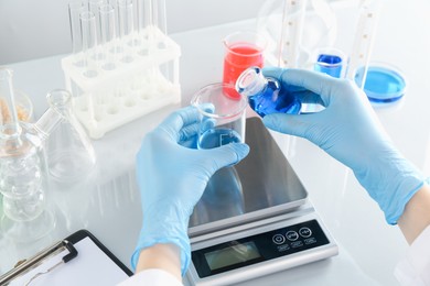 Photo of Scientist working with samples and scales at white mirror table in laboratory, closeup