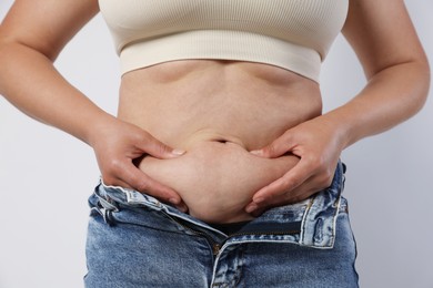 Photo of Woman with excessive belly fat on light background, closeup. Overweight problem