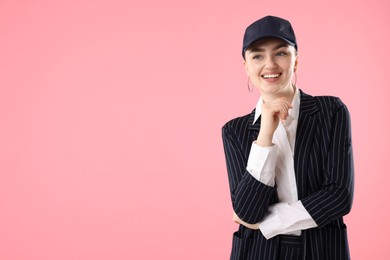 Photo of Smiling woman in stylish baseball hat on pink background. Space for text