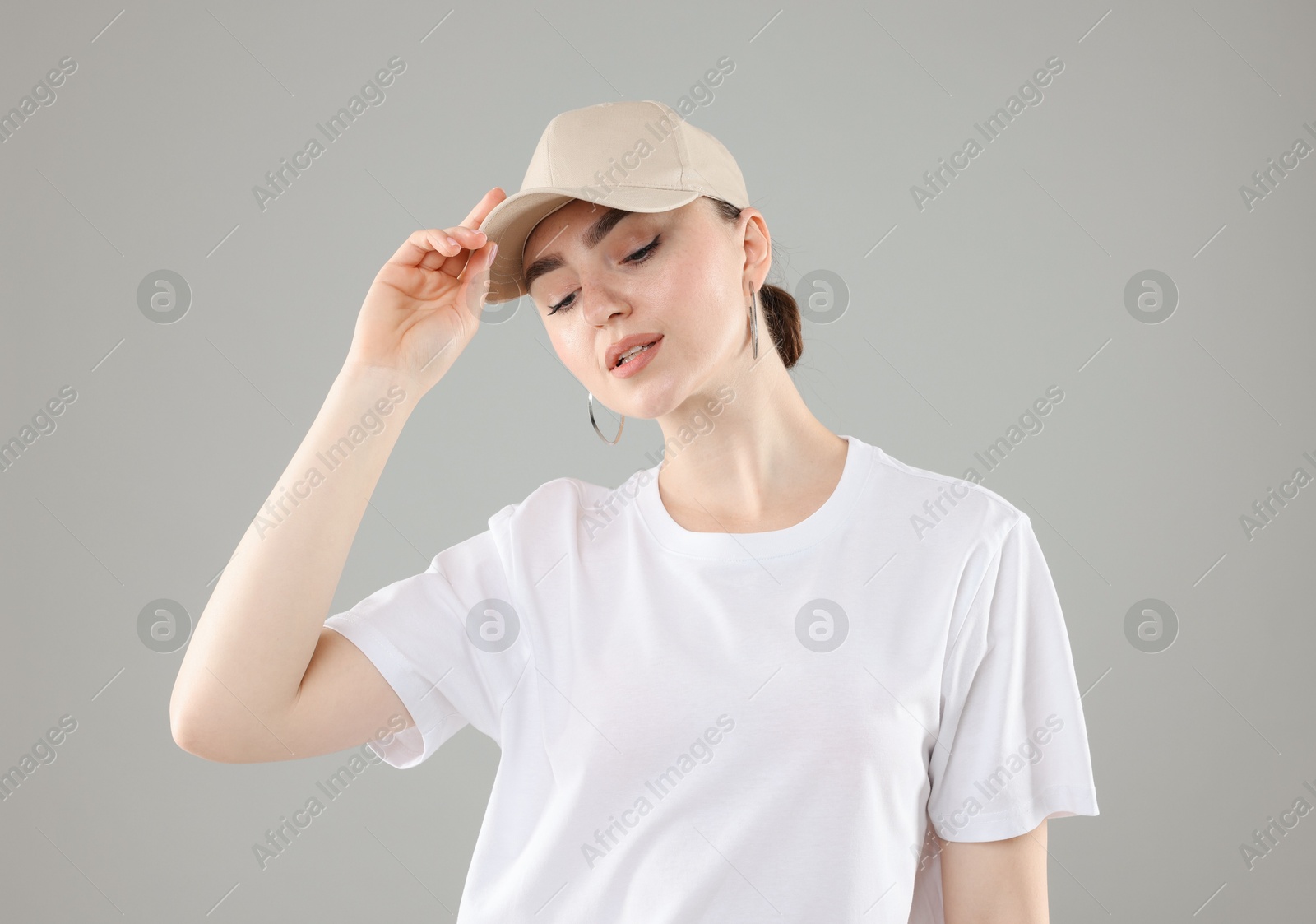 Photo of Beautiful woman in stylish baseball hat on grey background