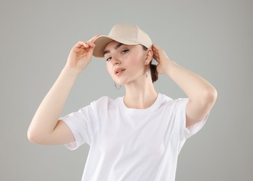 Photo of Beautiful woman in stylish baseball hat on grey background