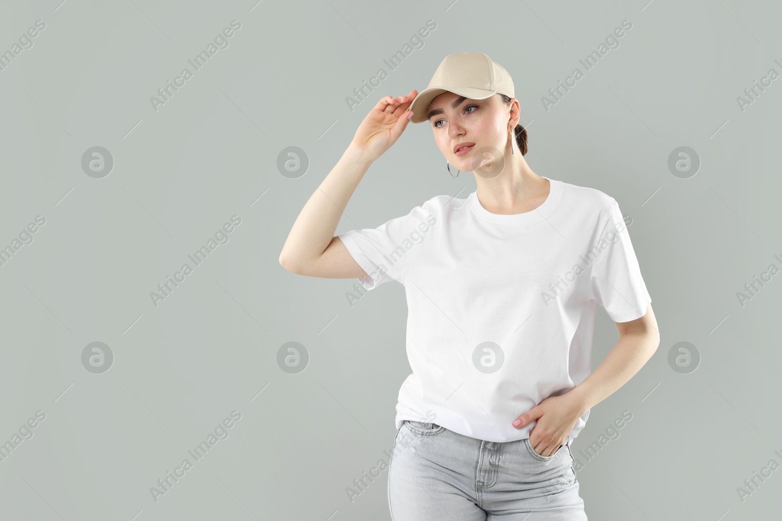 Photo of Beautiful woman in stylish baseball hat on grey background. Space for text